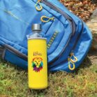 Yellow water bottle with lion logo next to a blue backpack on grass.