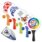 Five branded paddles with colorful handles and logos, three balls, and a mesh bag with a logo.