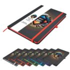 Stack of black notebooks with colorful elastic bands in red, orange, green, blue, purple, and black. A diagonal color strip shows a geometric design with circular patterns. The notebooks have a pen holder and a red bookmark ribbon.