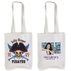 Two tote bags: one with a Jolly Roger Pirates design featuring a skull and crossed sabers, and the other with a photo of a smiling person next to books, along with text showing library hours and a URL for Uni Library.