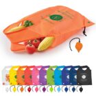 Reusable orange shopping bag with various vegetables spilling out, including corn and tomatoes. Below are more bags in different colors like white, yellow, pink, and blue, each with a small pouch attached at the bottom.