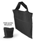 A black foldable tote bag with short handles is shown next to a smaller pouch made of the same material. Text beside the pouch reads, Folds up into this pouch.