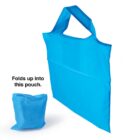 A bright blue reusable shopping bag is shown fully open beside its folded pouch form. The text Folds up into this pouch. is displayed next to the compact pouch.