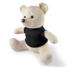 A cream-colored teddy bear is sitting upright, wearing a black T-shirt. Its arms and legs are spread slightly apart, and it has a round nose and oval eyes. The bear is positioned against a plain white background.