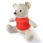 A soft plush teddy bear wearing a bright red shirt sits upright. Its beige fur and simplistic design give it a classic look. The bear has a round brown nose and small round eyes, exuding a friendly and cuddly appearance.