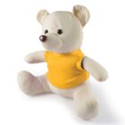 A plush teddy bear with beige fur is wearing a bright yellow shirt. It is sitting upright against a plain white background, looking slightly to the right. The bear has button eyes and a round brown nose.