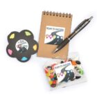 A stationery set includes a spiral notepad, a black pen, a flower-shaped sticky note pad with colored tabs, and a bag of jelly beans. All items feature a logo with the text ROAD TO SUCCESS and a road graphic.