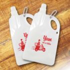 Two collapsible water bottles with carabiners on a wooden surface. Each features a red graphic of a delivery person on a scooter with the text Yum on a bike.