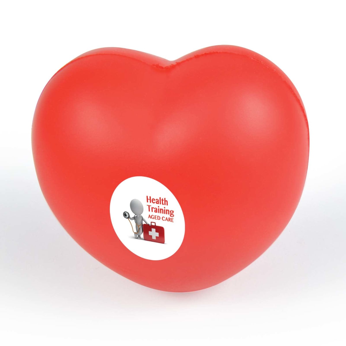 A red heart-shaped stress ball with a white sticker. The sticker features text and symbols related to health and training in aged care.