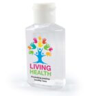A transparent hand sanitizer bottle with a white flip cap. The label features a tree with colorful handprints as leaves and the text LIVING HEALTH in green and pink, with Promoting positive healthy lives written below.