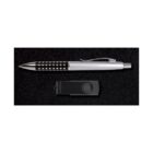 A silver and black ballpoint pen with a dotted grip lies above a closed black USB flash drive on a dark textured surface.
