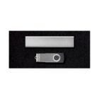 A silver rectangular USB flash drive and a silver metallic clip are placed on a black surface. The clip has a circular swivel mechanism for opening and closing.