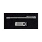 A silver pen and a silver USB flash drive with a swivel cover are placed on a black surface.