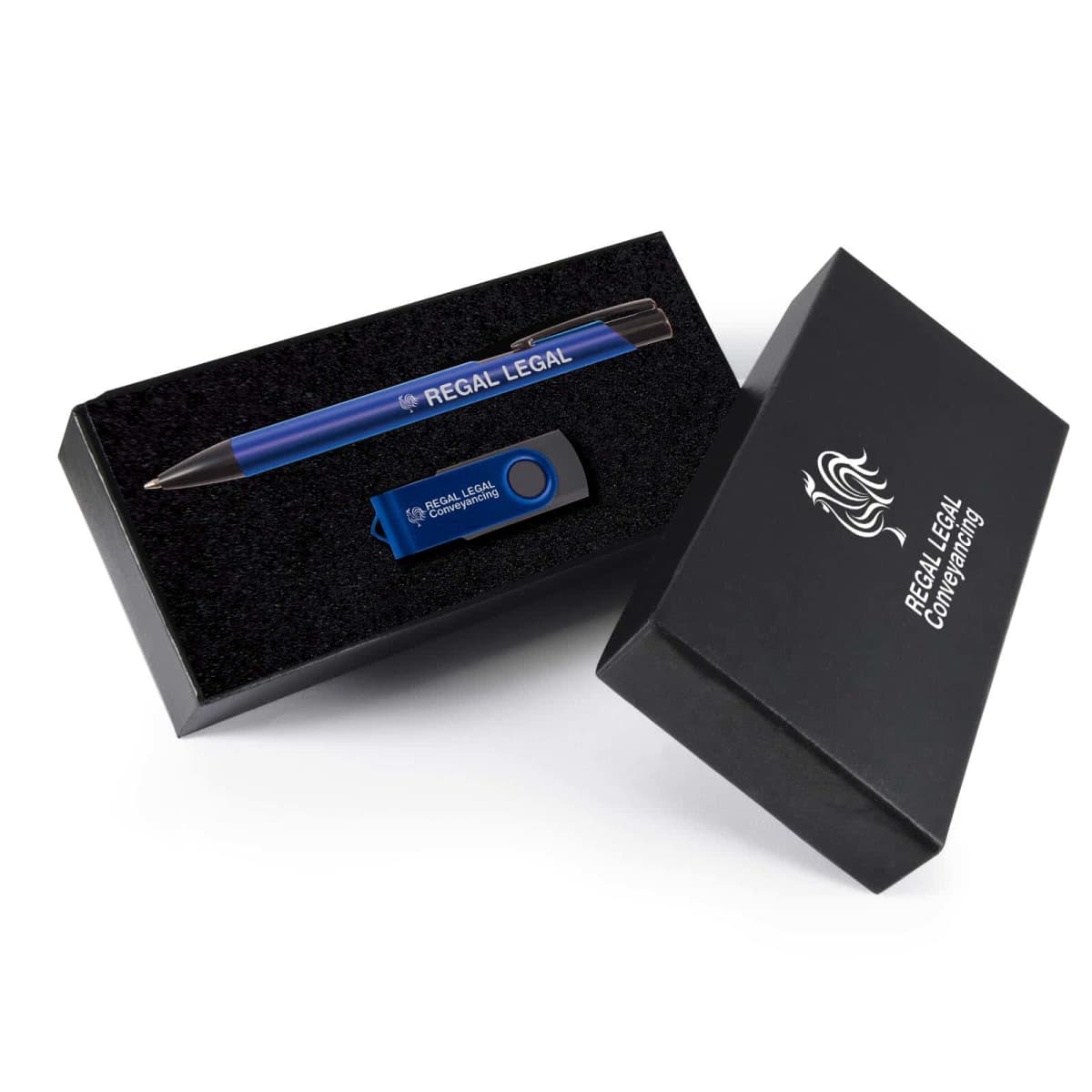 A branded gift set containing a blue pen and a USB flash drive with Regal Legal printed on them. Both items are placed in a black cushioned box, with the box lid featuring the Regal Legal Company logo in white.