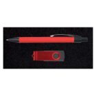 A red ballpoint pen with black accents lies horizontally above a red USB flash drive on a black textured background. The pen has a click mechanism, and the USB has a swivel cover.