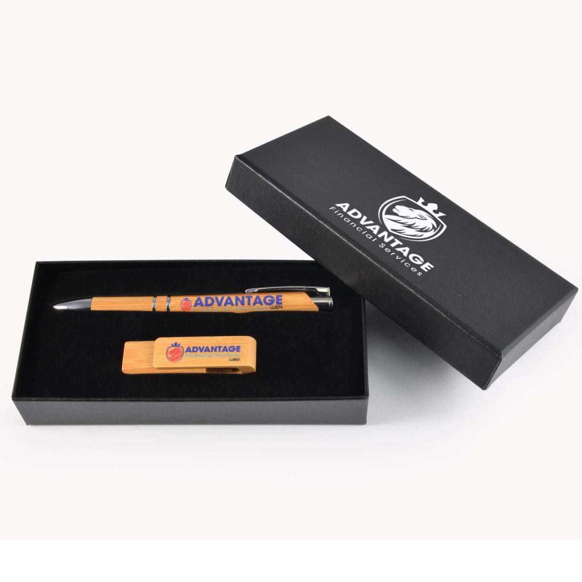 A black gift box with a logo on the lid is displayed open, revealing a bamboo pen and a USB drive inside. Both items have the word ADVANTAGE printed on them, with the USB also featuring a small apple design.