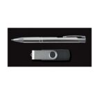 A silver ballpoint pen and a gray USB flash drive with a swivel cover are placed on a black background.