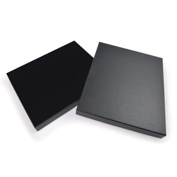 Two closed black boxes with a matte finish are placed side by side on a white background. One box is slightly leaning against the other, showcasing their sleek, minimalistic design.