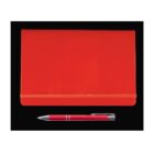 A closed red notebook with an elastic band is placed above a red pen with silver accents on a black background.
