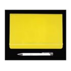 A closed yellow notebook with an elastic band is placed on a black background. Below the notebook, there is a white pen with a silver clip.