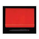 A red notebook with an elastic band lies closed on a black surface. Below the notebook is a black pen with a red tip.