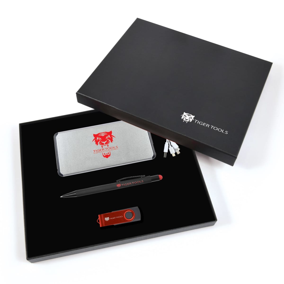 Gift set with Tiger Tools branding on a black box. Inside, a silver power bank, black pen, orange USB drive, and charging cables are neatly arranged on a black fabric lining.
