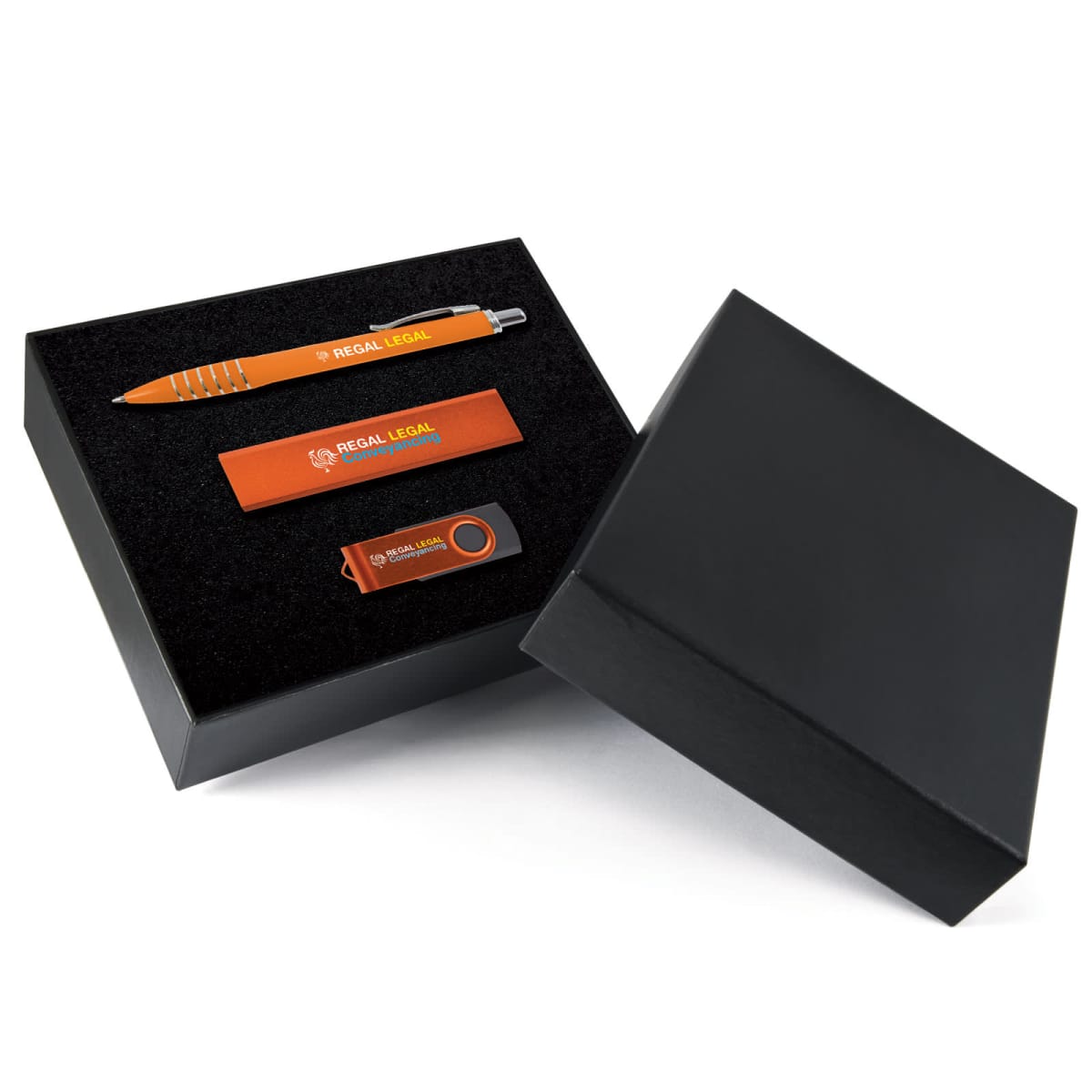 A gift box with a branded pen, USB drive, and rectangular keychain, each labeled REGAL LEGAL. The items are arranged neatly in a black box with the lid partially off.