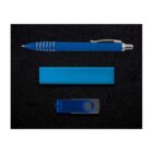 A blue pen with silver accents, a rectangular blue power bank, and a blue USB flash drive with a black swivel cover are arranged neatly in a line on a textured black background.