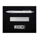 A white pen, a rectangular silver block, and a silver USB flash drive are arranged neatly on a black textured surface.