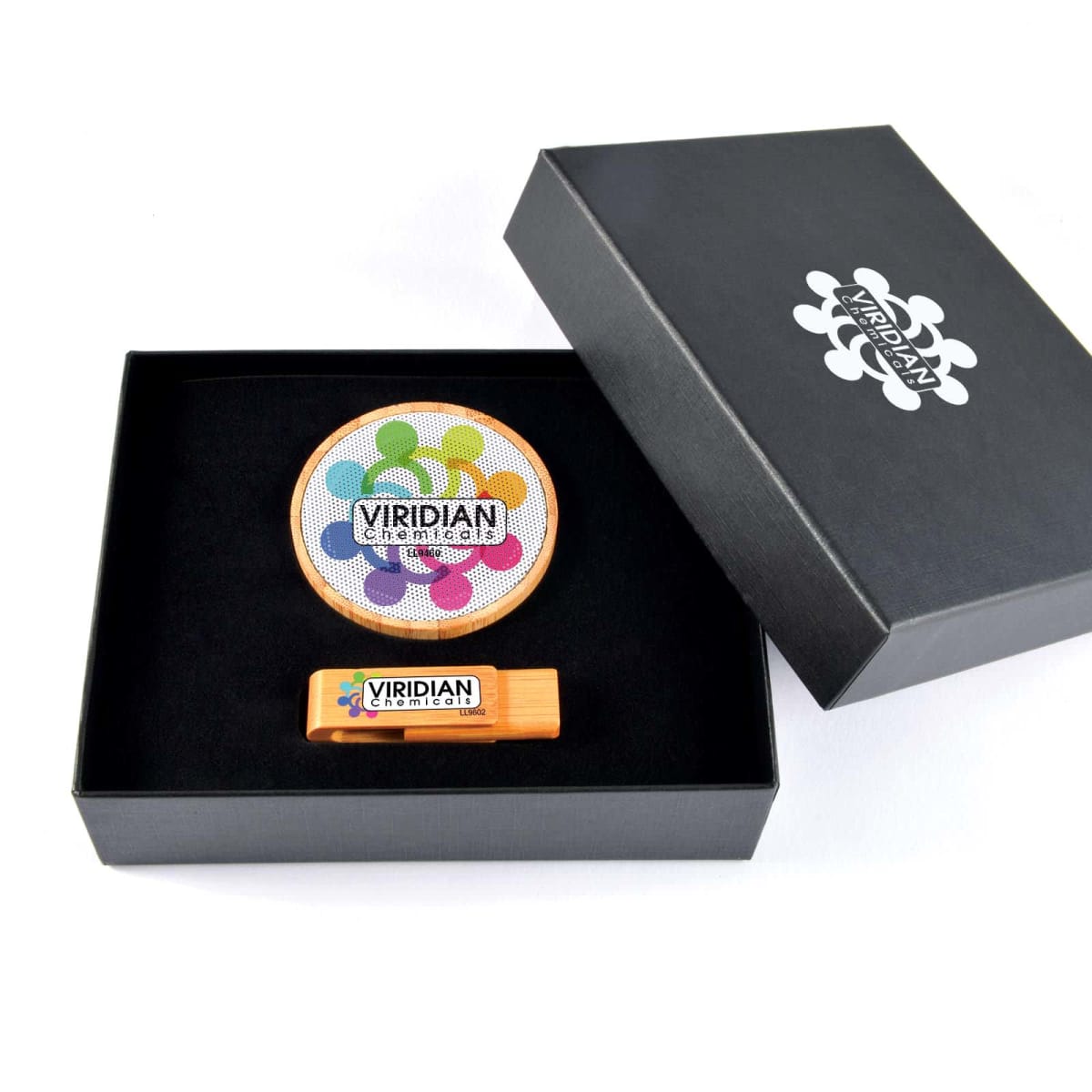 Open black box containing a circular coaster with a colorful interconnected people design and Viridian text, alongside a rectangular product labeled Viridian. The box lid displays a similar interconnected people motif.