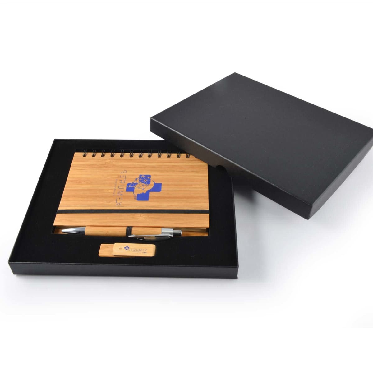 A gift set in a black box contains a bamboo notebook with a blue logo, a bamboo pen, and a USB drive. The notebook and pen are aligned neatly, with the pen above the USB drive. The box lid is partially open.