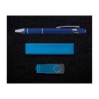 A blue pen with a silver tip, a rectangular blue power bank, and a blue USB flash drive are arranged on a textured black background.