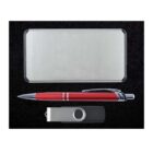 A silver rectangular business card holder, a red pen with silver accents, and a USB flash drive with a silver and black body are arranged neatly on a black background.