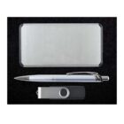 A rectangular silver metal business card holder, a silver ballpoint pen with a textured grip, and a silver USB flash drive with a black cap are arranged neatly on a black background.
