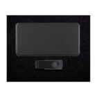 A black rectangular phone with no visible branding is placed above a black USB drive on a dark speckled surface. The USB drive has a circular design element. The overall aesthetic is sleek and modern.
