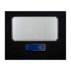 A rectangular silver power bank and a blue USB flash drive with a swivel cover are placed on a black textured surface.