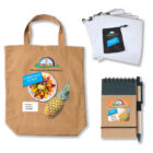 A beige tote bag with Woolstoncraft Marketplace logo and a pineapple image, a set of cloth bags, a notebook, and a pen. All items feature the same marketplace branding and colorful pineapple design.