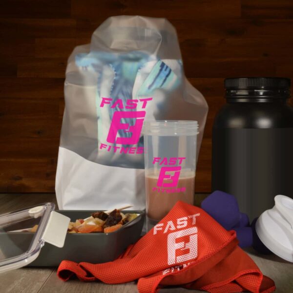 Fitness-themed composition with a shaker bottle, protein bag, dumbbells, and a large black container. A red towel labeled FAST FITNESS and a meal prep container with salad are also present, set against a wooden background.