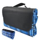 Foldable blue plaid picnic blanket with a black carry handle. The blanket is shown folded up with a portion of the blue plaid pattern visible, and a smaller rolled-up version is also shown alongside.