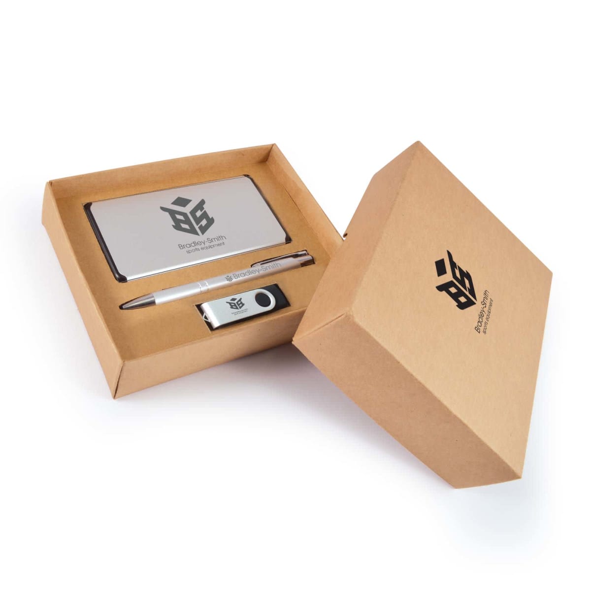 A brown cardboard box holds branded corporate gifts, including a silver power bank, a pen, and a USB drive, all featuring a black logo. The open lid reveals the contents neatly arranged inside.