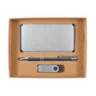 A cardboard gift box containing a silver metal business card holder, a silver pen, and a silver USB flash drive, all neatly arranged side by side.