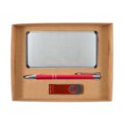 A cardboard box containing a silver business card holder, a red pen with silver accents, and a red USB flash drive with a metal swivel cover.