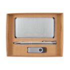 A brown gift box containing a silver business card holder, a silver pen, and a silver USB flash drive. The items are neatly arranged in compartments.