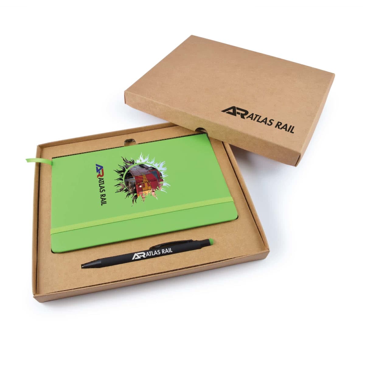 A gift set includes a green notebook with a colorful train design and Atlas Rail logo, and a black pen with the same logo. The set is housed in an open brown cardboard box.
