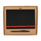 A black notebook with a red elastic band is placed inside an open brown cardboard box. Below the notebook, there is a black pen with a blue tip.