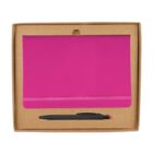 A pink notebook with an elastic band is presented in a brown cardboard box. Below the notebook, theres a black pen with a red top. The cardboard box has a cutout at the top for easy opening.