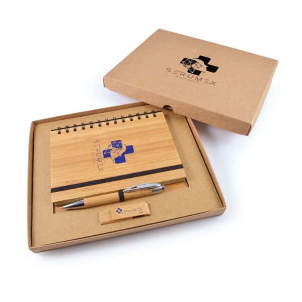 Box set with a wooden cover notebook, pen, and USB drive. The notebook has a spiral binding and an elastic band. The pen and USB have wooden accents. The box, with STRUMEX and a logo, is open to display the items neatly.