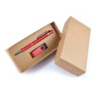 A brown cardboard box open to reveal a red pen and a red USB flash drive inside. The pen has a silver clip and tip, and the USB drive is encased in a rectangular black and red casing.