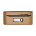 A ballpoint pen and a USB flash drive are placed inside an open rectangular cardboard box. The pen is black with a metallic clip, while the USB drive is white with a circular black design.