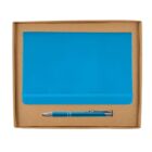 A blue notebook and pen set inside a brown cardboard box. The notebook has an elastic band and the pen features a metallic clip.